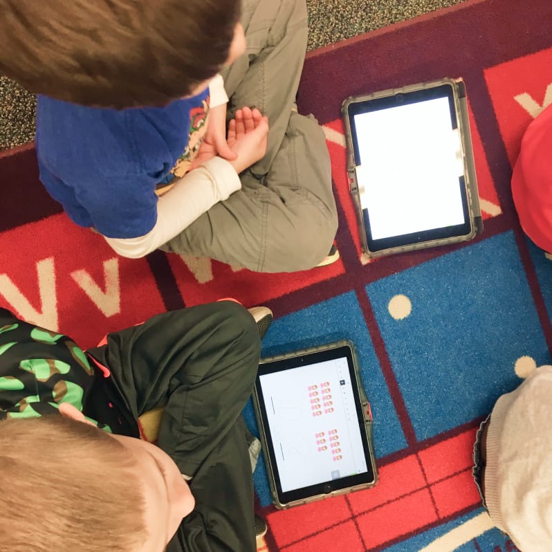 Two students sitting on the floor using Classkick on their tablets