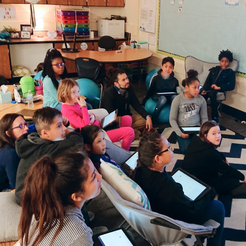 Room of seated students looking up at a teacher