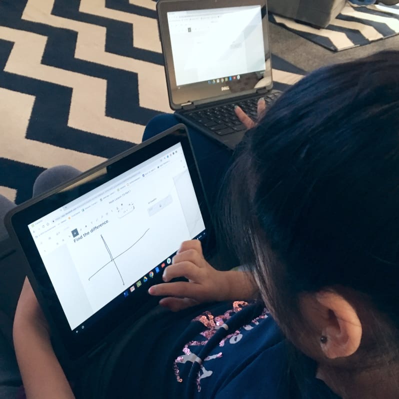 Two students sitting on the floor working on laptops